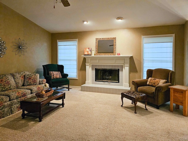 carpeted living room with a tile fireplace and ceiling fan