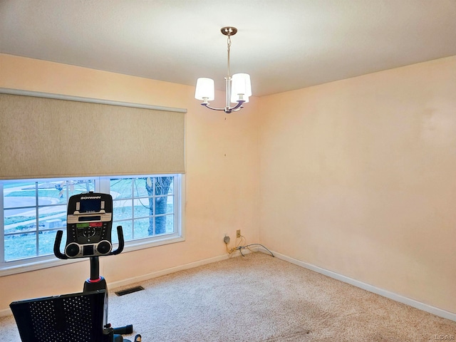 exercise area featuring carpet flooring and a notable chandelier