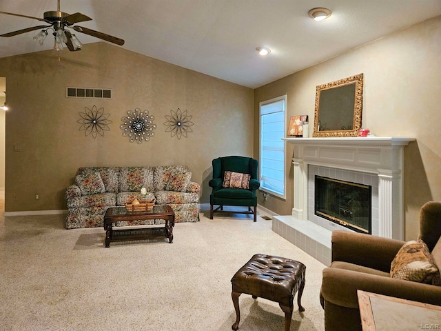 carpeted living room with ceiling fan, lofted ceiling, and a tiled fireplace