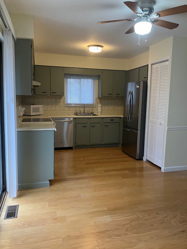 kitchen with decorative backsplash, appliances with stainless steel finishes, light hardwood / wood-style floors, and sink