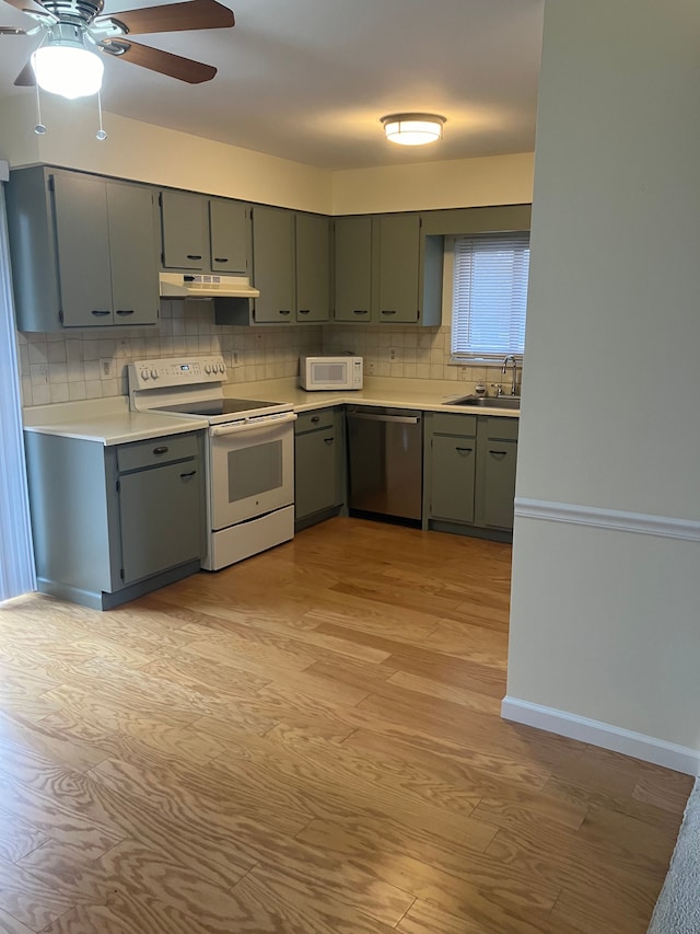 kitchen featuring white appliances, sink, decorative backsplash, ceiling fan, and light hardwood / wood-style floors