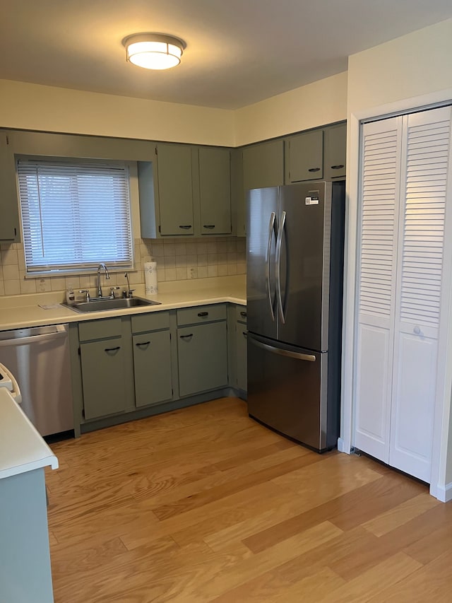 kitchen featuring appliances with stainless steel finishes, backsplash, light hardwood / wood-style floors, and sink