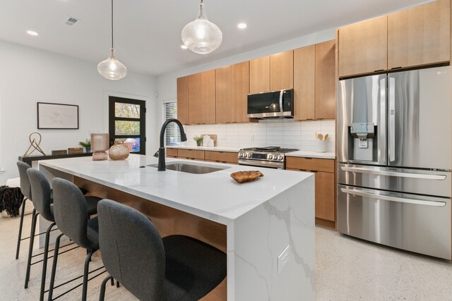 1636 Merrick St Unit 8, Detroit, MI 48208 - kitchen featuring appliances with stainless steel finishes, a sink, tasteful backsplash, a center island with sink, and a kitchen bar