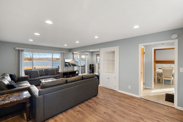 living room with a textured ceiling, light wood finished floors, baseboards, and recessed lighting
