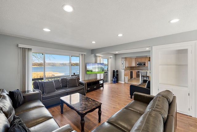 living area featuring light wood finished floors, baseboards, a textured ceiling, and recessed lighting