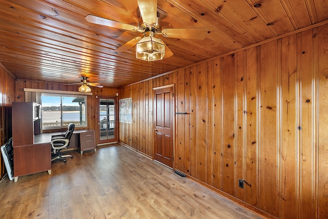 unfurnished office with wooden ceiling, built in desk, ceiling fan, wood walls, and light wood-style flooring