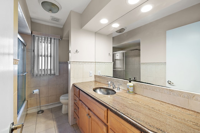 full bath featuring toilet, vanity, visible vents, tile walls, and tile patterned floors