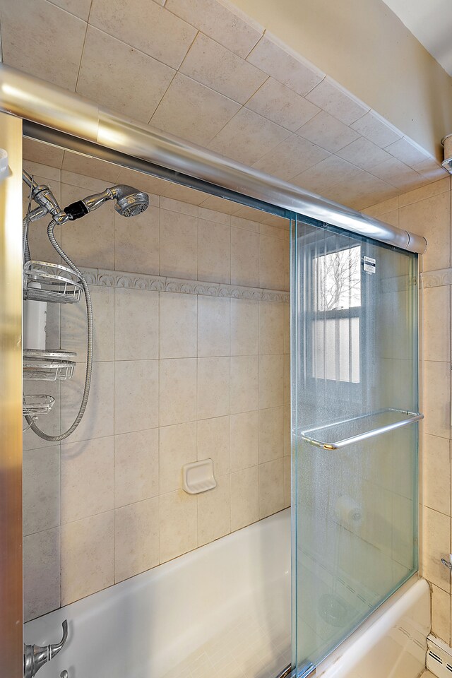 bathroom featuring combined bath / shower with glass door