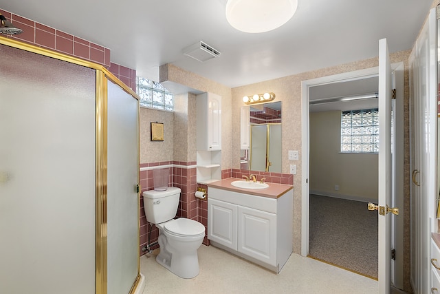 bathroom with vanity, visible vents, toilet, tile walls, and a stall shower