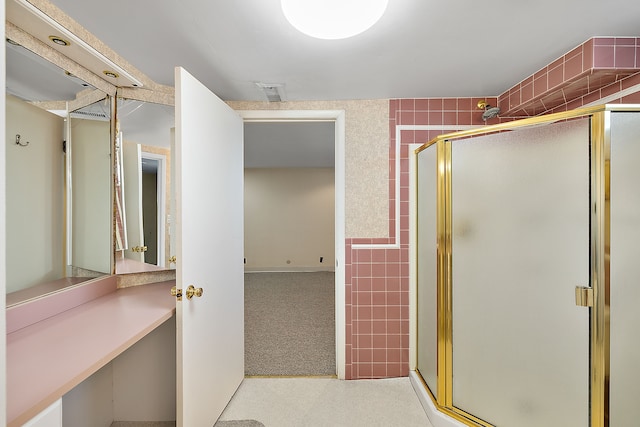 bathroom with a shower with door and tile walls