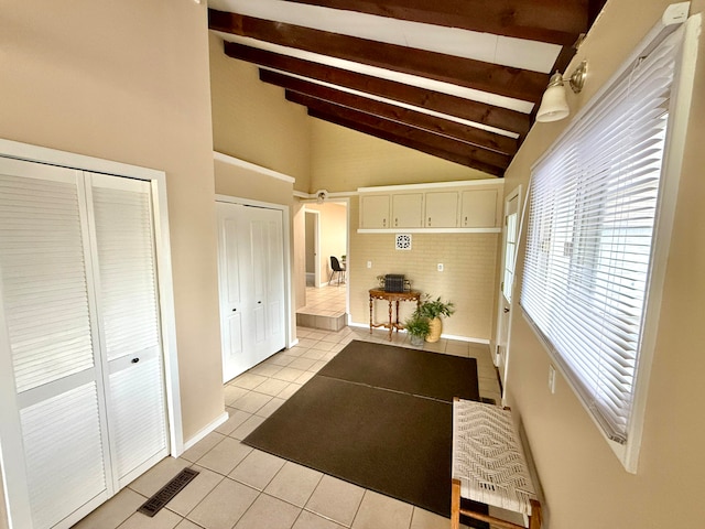 hall with light tile patterned floors and vaulted ceiling with beams