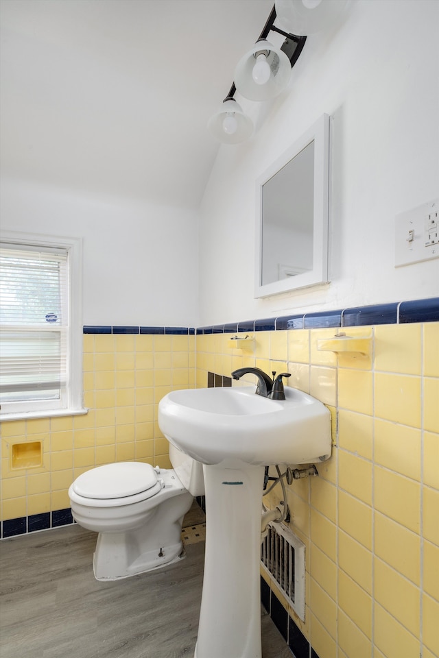 bathroom with toilet, wood-type flooring, and tile walls