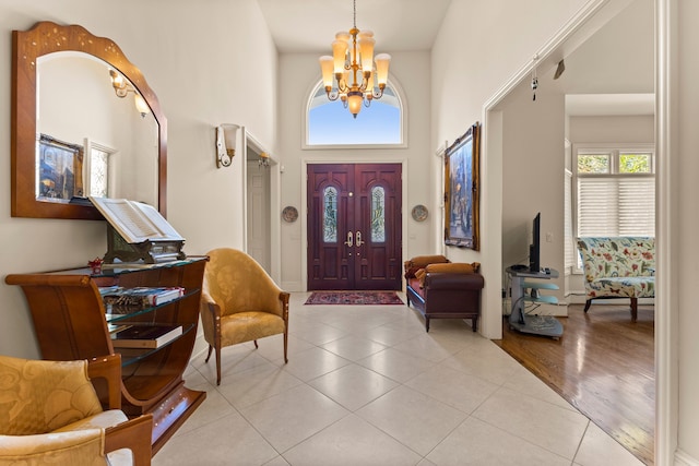 foyer entrance with a chandelier, a towering ceiling, light hardwood / wood-style flooring, and a healthy amount of sunlight