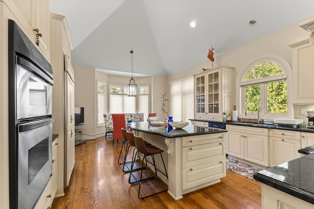 kitchen with a center island, sink, hardwood / wood-style flooring, cream cabinetry, and stainless steel double oven