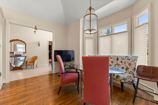 dining room with breakfast area, lofted ceiling, dark wood-type flooring, and a baseboard radiator