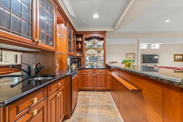 bar with decorative columns, dark stone countertops, and light tile patterned floors