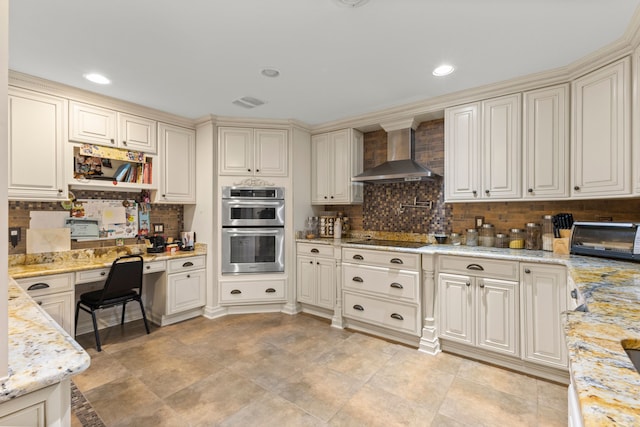 kitchen with light stone countertops, wall chimney range hood, double oven, black electric cooktop, and decorative backsplash