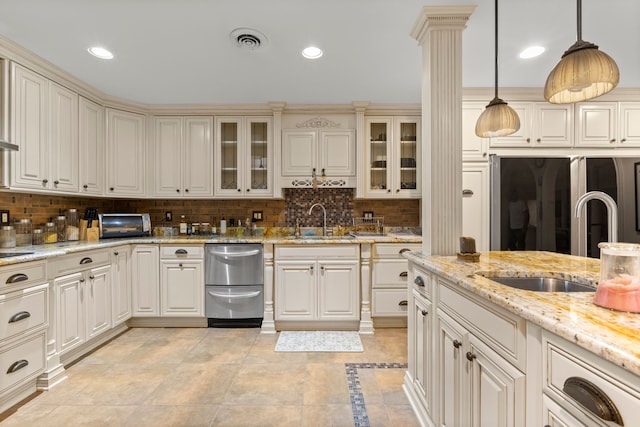 kitchen with decorative backsplash, light stone countertops, sink, and decorative light fixtures