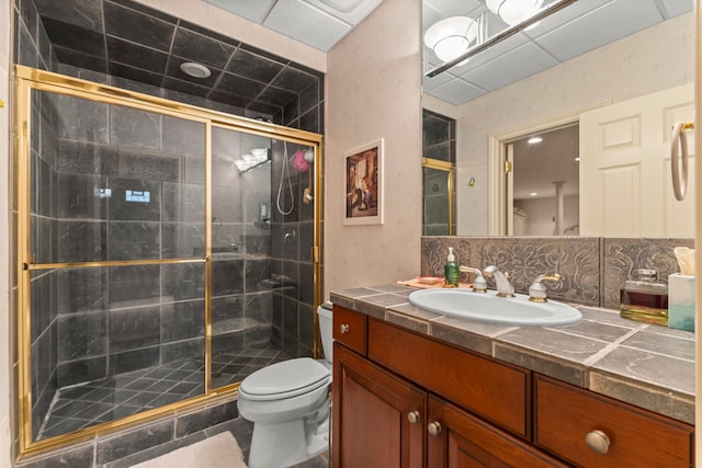 bathroom with backsplash, a shower with door, vanity, and toilet