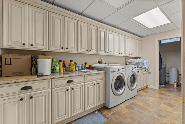 clothes washing area with washing machine and clothes dryer, light tile patterned floors, and cabinets