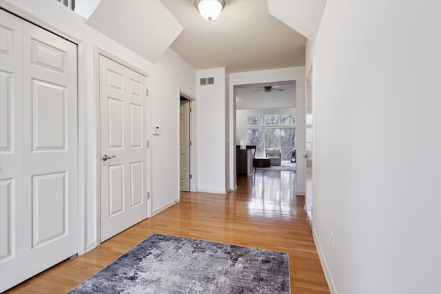 corridor featuring baseboards, visible vents, and light wood-style floors