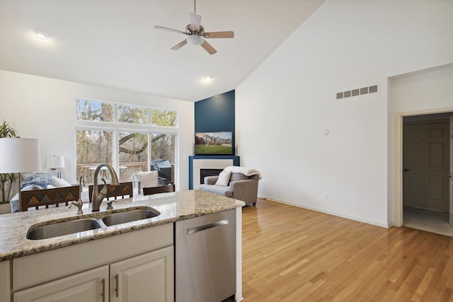 kitchen with a fireplace, visible vents, stainless steel dishwasher, open floor plan, and a sink