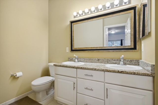 full bath featuring toilet, double vanity, a sink, and tile patterned floors