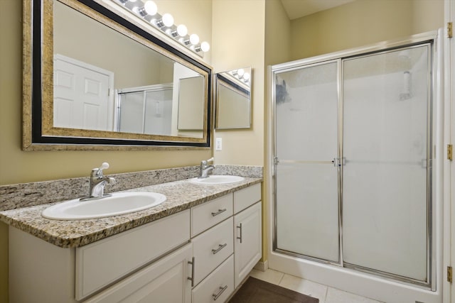 full bath with double vanity, a stall shower, a sink, and tile patterned floors