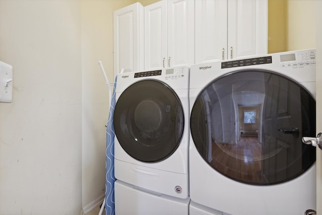 clothes washing area featuring separate washer and dryer and cabinet space