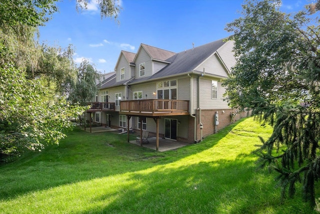 rear view of property with a deck, a patio, brick siding, and a lawn