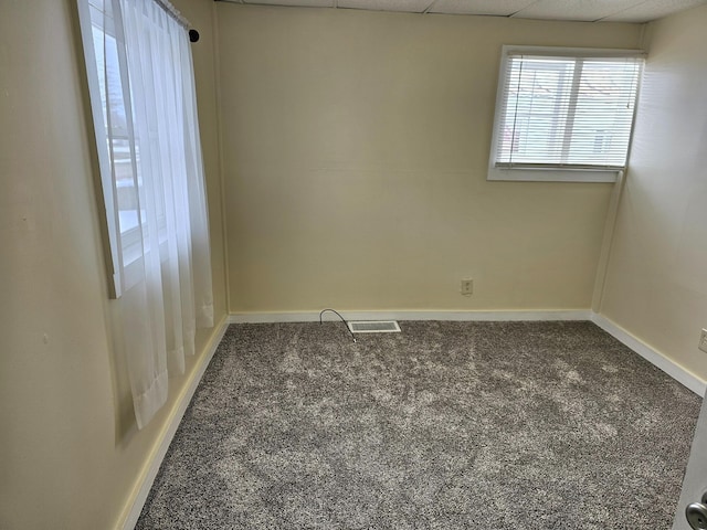 carpeted empty room featuring a drop ceiling