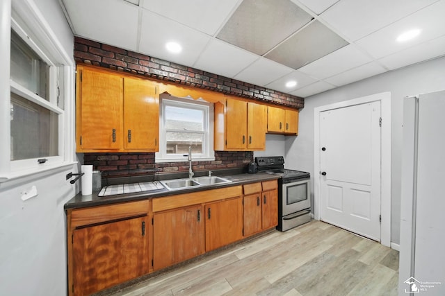 kitchen featuring stainless steel electric range oven, sink, decorative backsplash, a drop ceiling, and light wood-type flooring