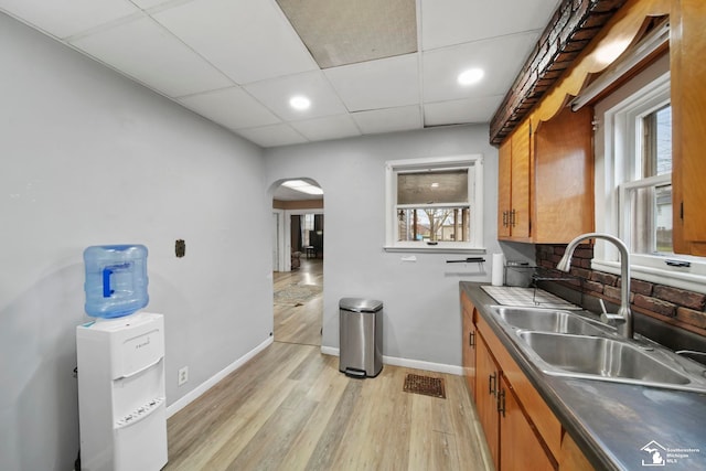 kitchen with sink, backsplash, a paneled ceiling, and light hardwood / wood-style floors