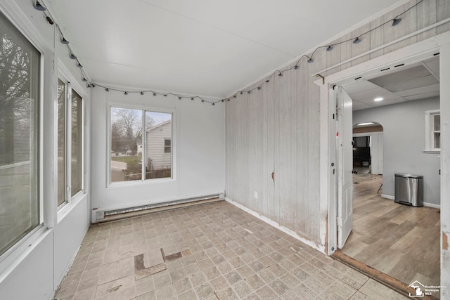 spare room featuring baseboard heating, light wood-type flooring, and wood walls