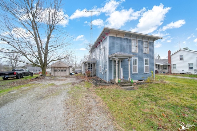 view of front of property with a garage, an outdoor structure, and a front lawn