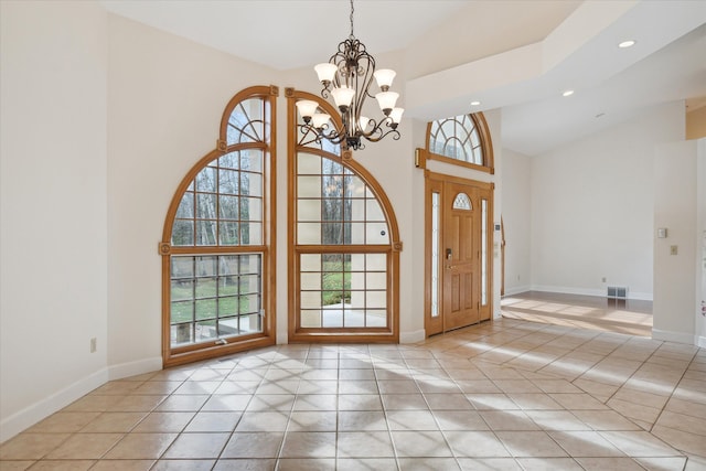 tiled entrance foyer featuring high vaulted ceiling and a chandelier