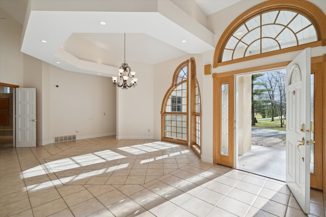 tiled foyer with a towering ceiling and a chandelier