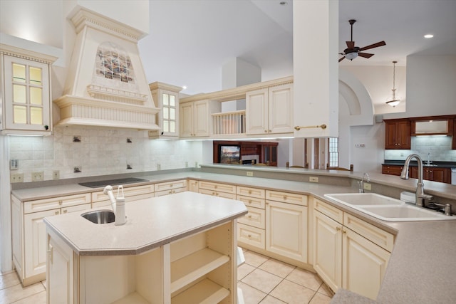 kitchen featuring black electric stovetop, ceiling fan, sink, decorative light fixtures, and cream cabinetry