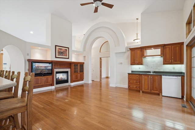 kitchen featuring white dishwasher, light hardwood / wood-style floors, sink, and high vaulted ceiling