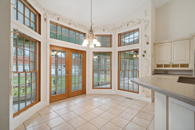 unfurnished dining area with french doors, high vaulted ceiling, a chandelier, and light tile patterned floors