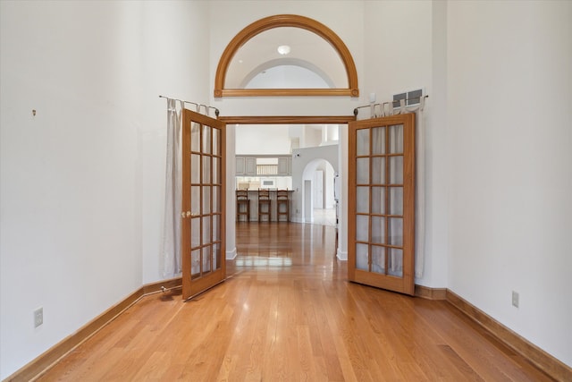 spare room featuring french doors, a high ceiling, and light wood-type flooring