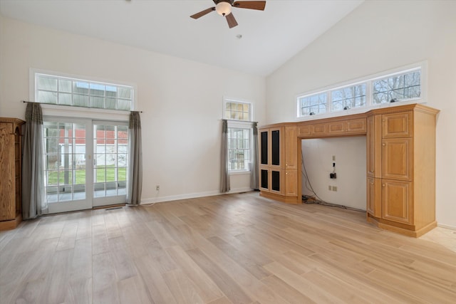 unfurnished living room with ceiling fan, plenty of natural light, light hardwood / wood-style floors, and high vaulted ceiling