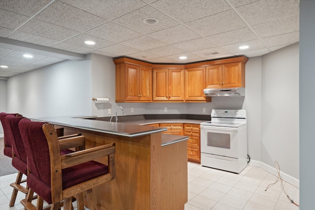 kitchen featuring white range with electric cooktop, a kitchen breakfast bar, light tile patterned flooring, and kitchen peninsula