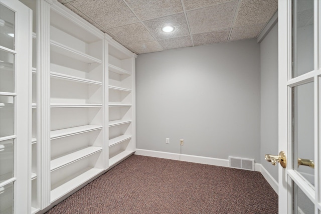 spare room featuring a paneled ceiling and dark carpet