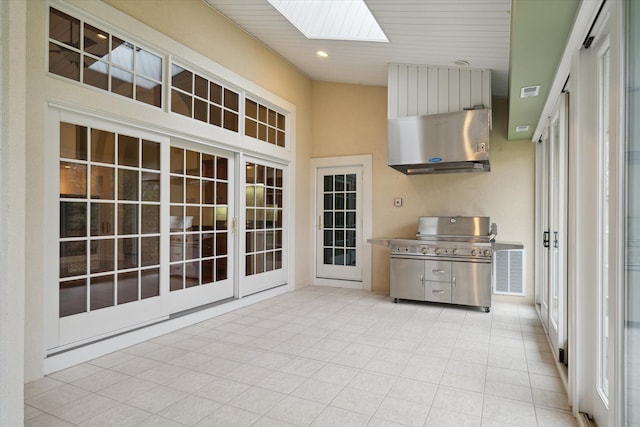 kitchen with ventilation hood, light tile patterned flooring, a towering ceiling, and a skylight