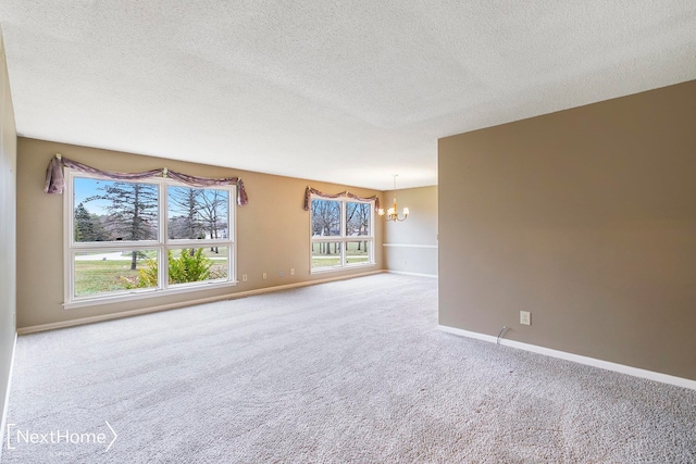 carpeted empty room with a notable chandelier and a textured ceiling