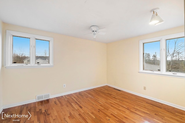 empty room with hardwood / wood-style flooring, ceiling fan, and a healthy amount of sunlight