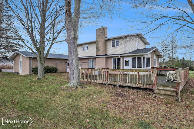 rear view of property featuring a sunroom, a deck, and a yard