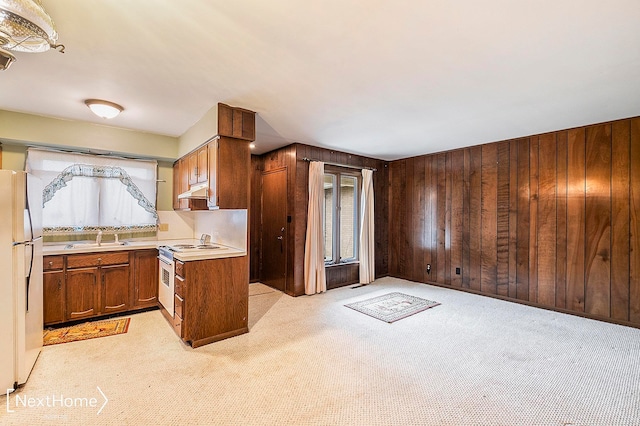 kitchen with wood walls, white appliances, and light carpet