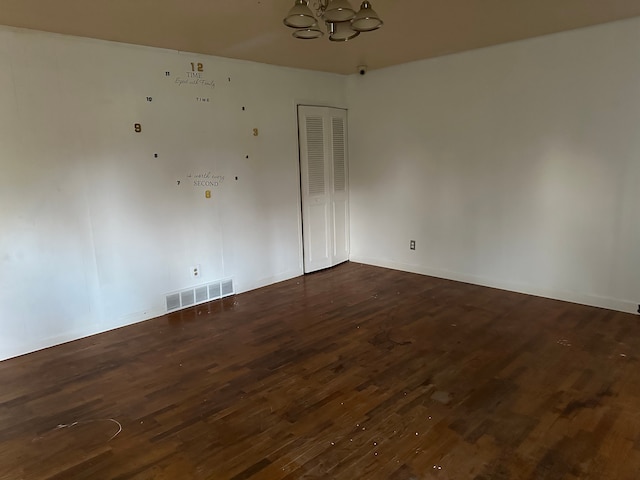 unfurnished room featuring dark hardwood / wood-style flooring and an inviting chandelier